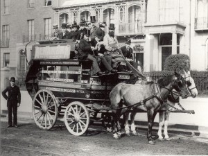 Men in top hats sitting on a horse drawn omnibus