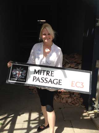 Tour guide Lindsay Siviter holding the Mitre Passage sign.