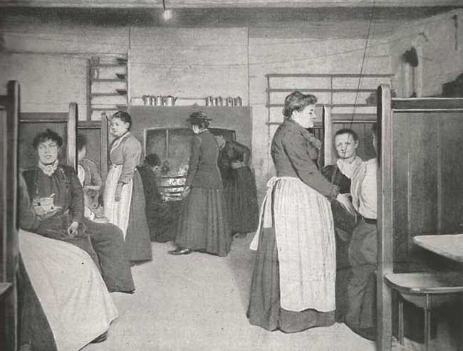 Women sit at tables in a Common Lodging House Kitchen