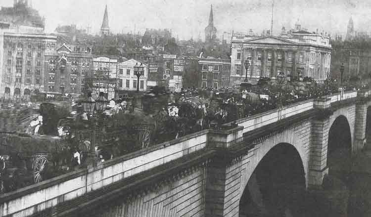 A view of the Victorian London Bridge with horses and carts crossing it.