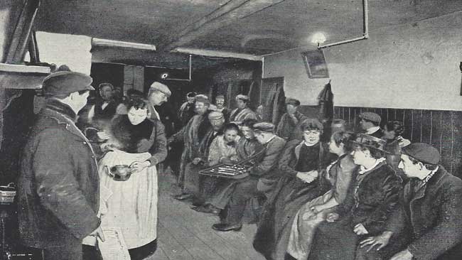 A group of people sitting and being served tea in a common lodging house.