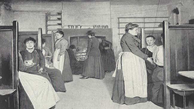 Men and women inside the kitchen of a common lodging house.